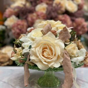 Centrotavola con fiori artificiali composto da rose e decorazioni realizzato in un'alzata in vetro verde Ø 28 cm