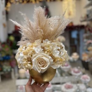 Centrotavola, Ampolla oro in vetro con fiori artificiali composto da boccioli di rose panna in velluto, ortensie e pampas Ø 25 cm